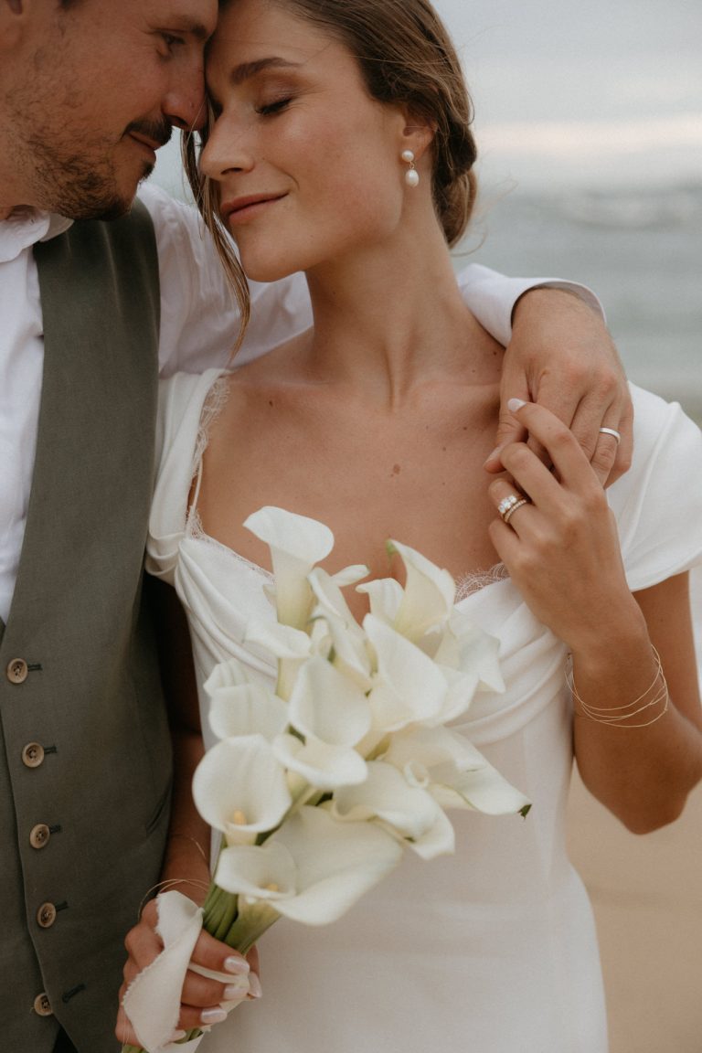 Le marié prend sa femme sous son bras et pose son front contre le sien. Ils sourient en partageant ce moment de tendresse pendant la séance couple le jour de leur mariage avec par Lesley Sanchez, photographe Landes.